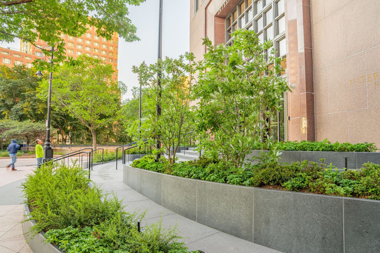 Wide concrete steps with metal railings and landscaped planters at building entrance.