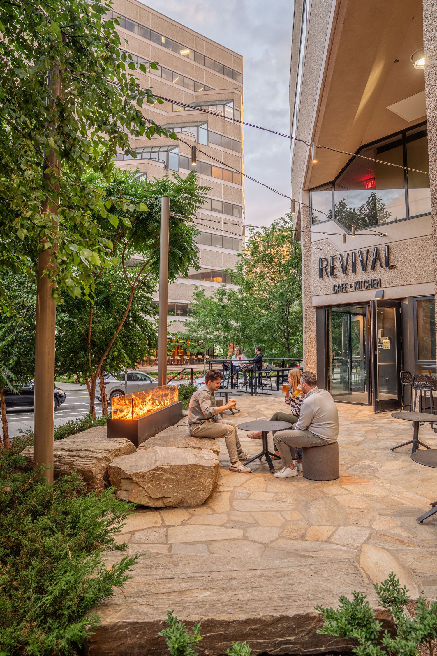 Modern urban plaza with stone seating and landscaping features outside a commercial building entrance.