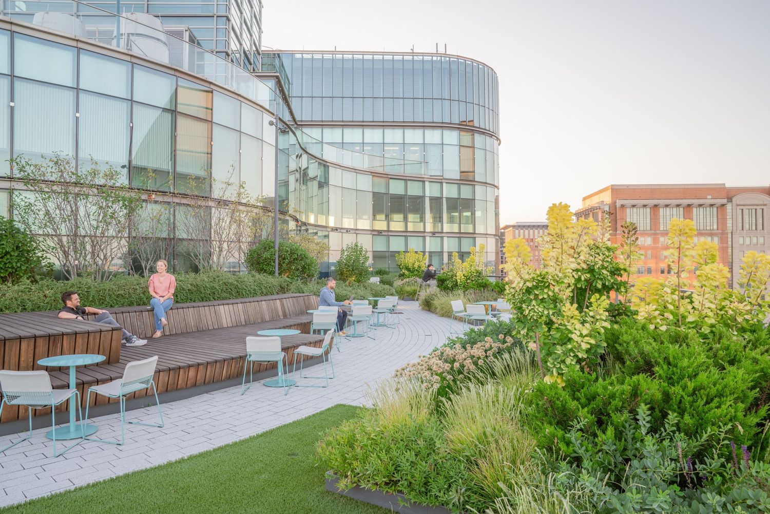 Urban rooftop garden with curved glass building facade and landscaped greenery.