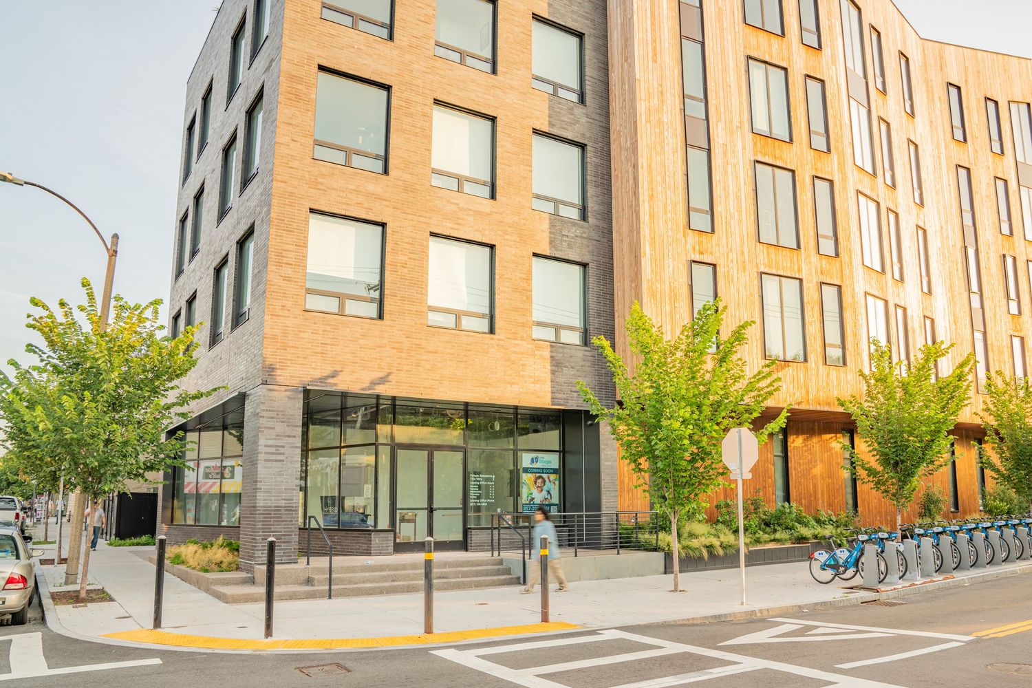 Modern apartment building exterior with angular architecture and large windows in warm sunlight.