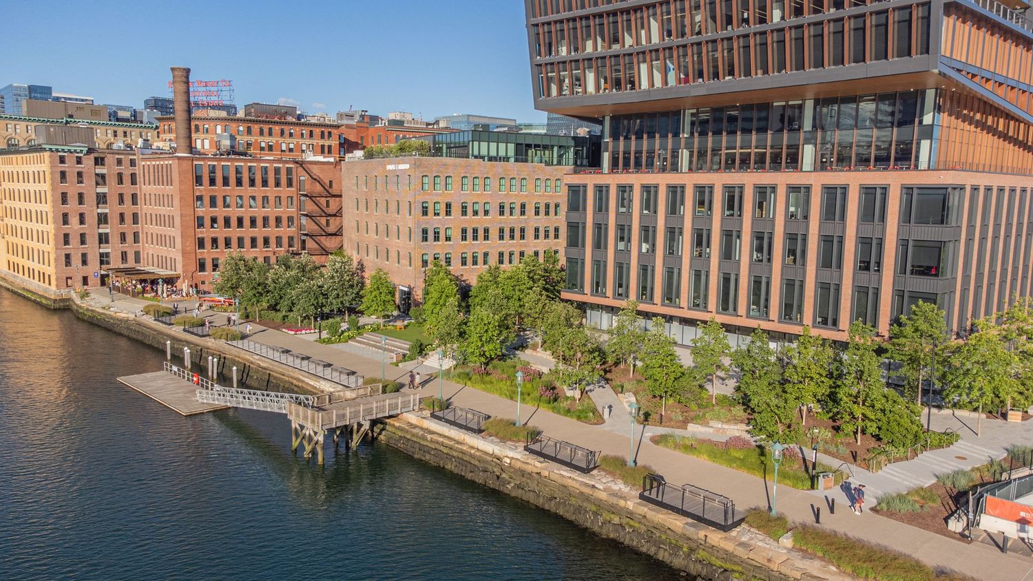 Panoramic waterfront view of historic brick buildings along an urban harbor.