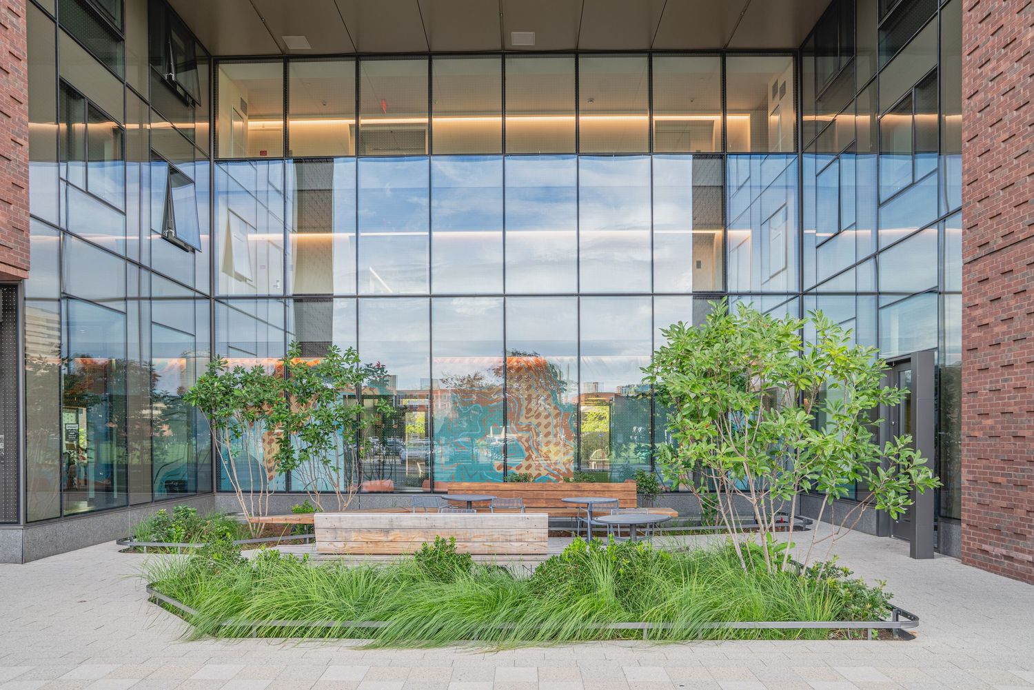 Modern brick and glass building exterior with landscaped entrance walkway and planters.