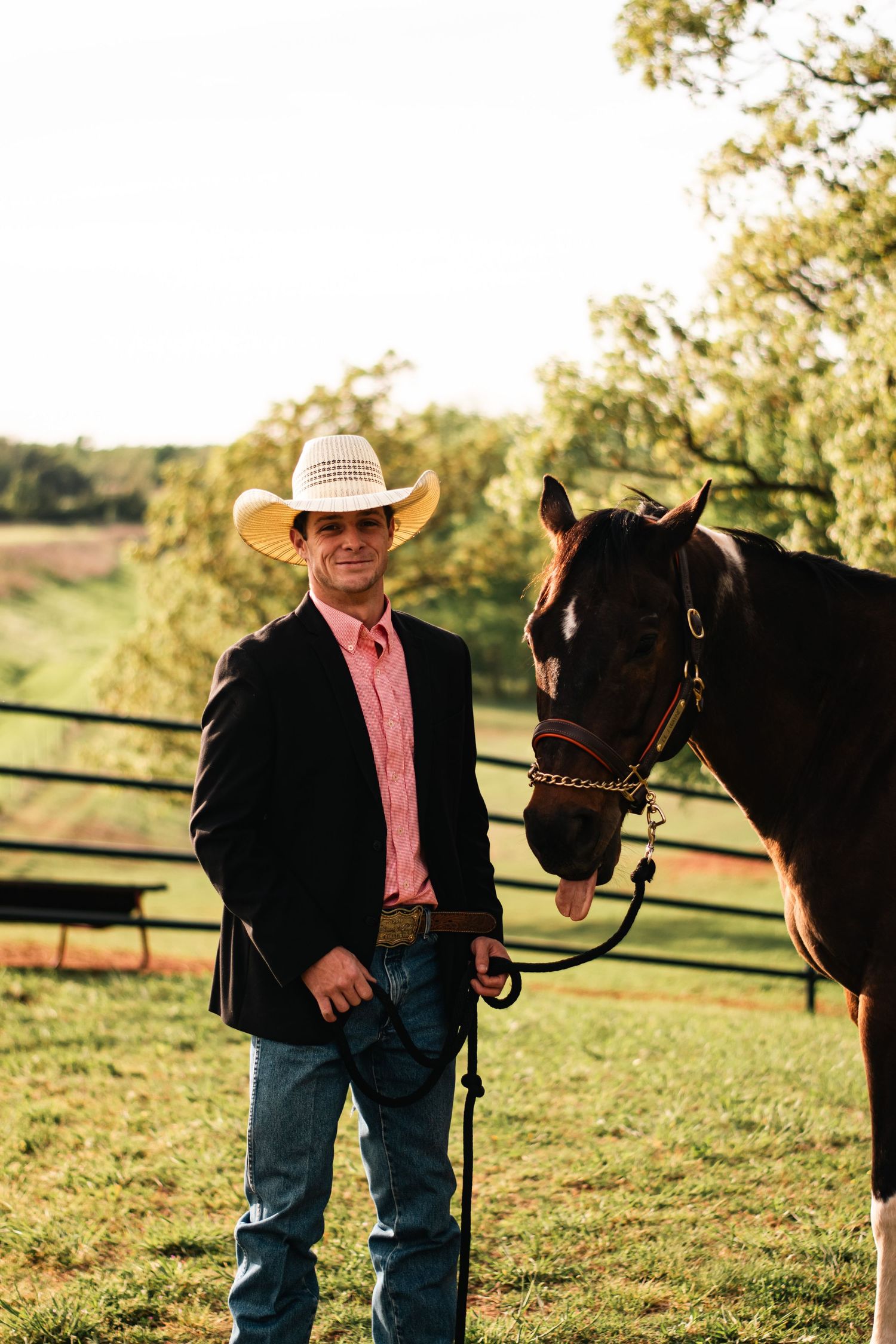 Western portrait photography of a young man in cowboy hat and blazer with his horse, captured outdoors in warm natural evening light.