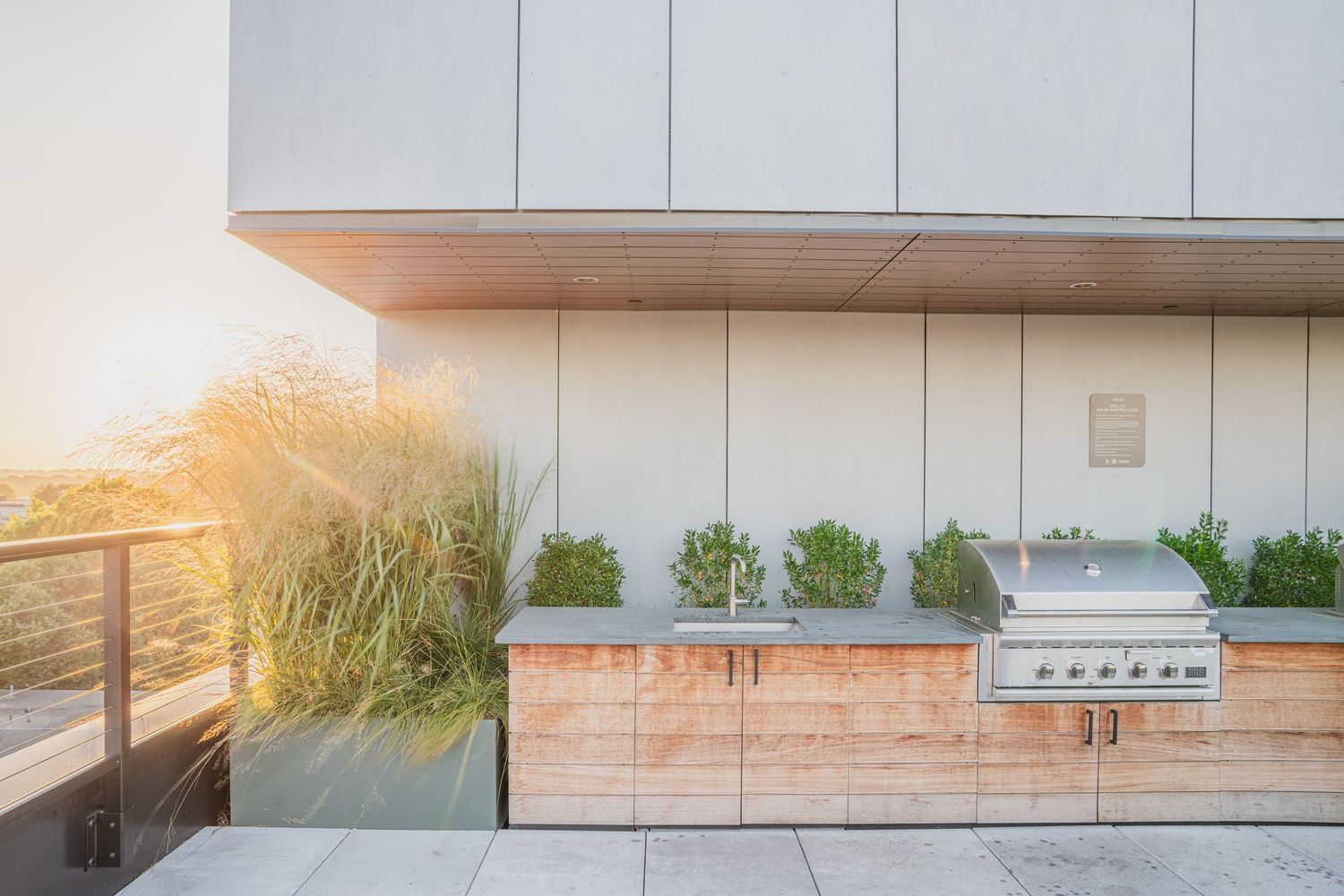 Sleek modern outdoor kitchen area with white cabinets and stainless steel appliances.