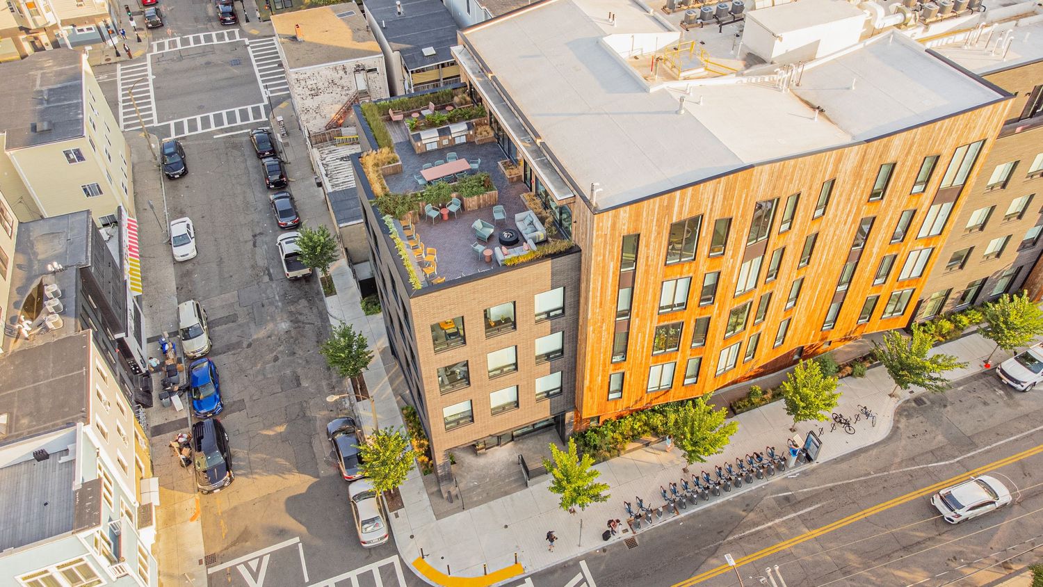 Overhead view of urban apartment buildings with parked cars and landscaped grounds.