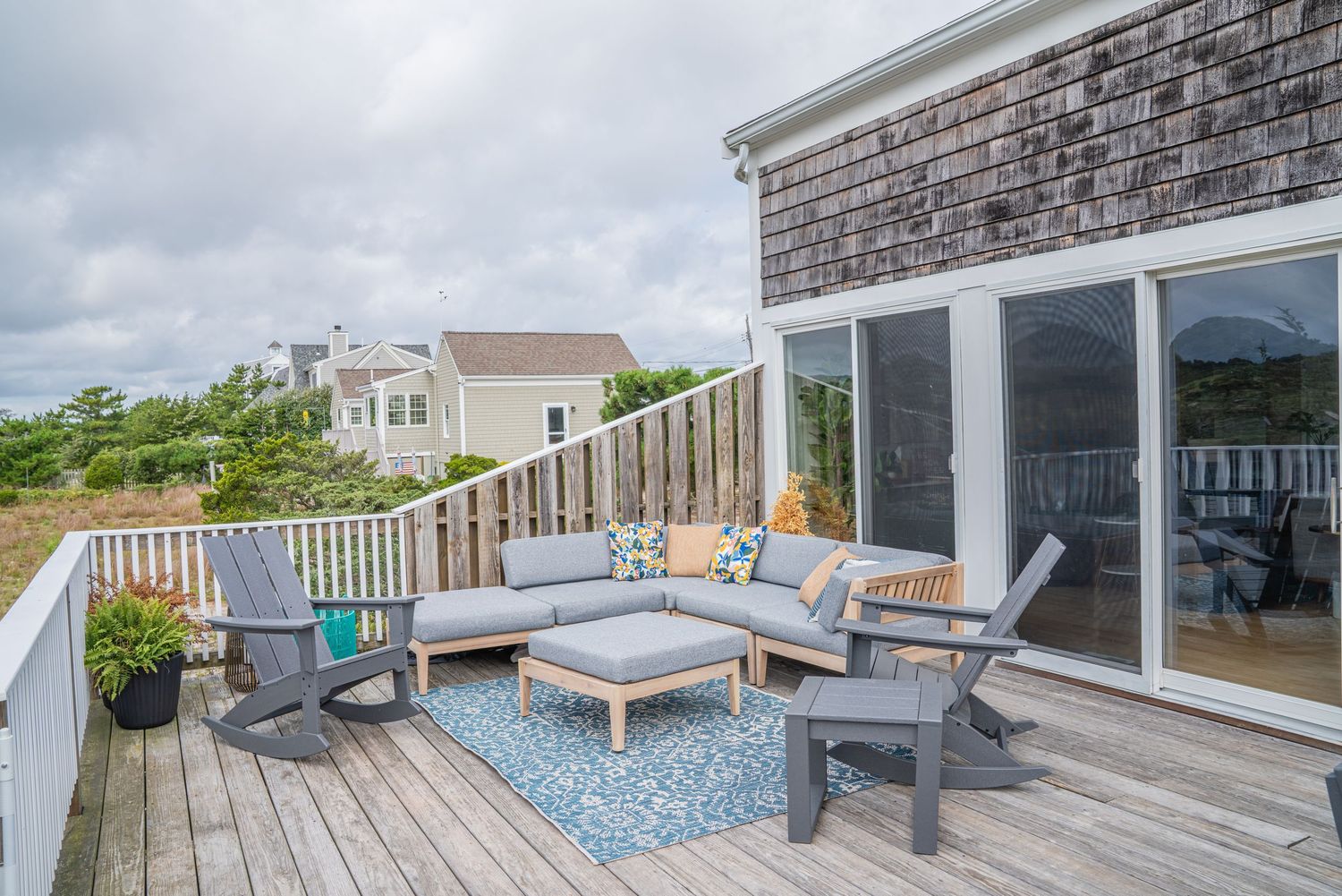 Spacious outdoor deck with gray composite flooring and glass railings overlooks coastal scenery.
