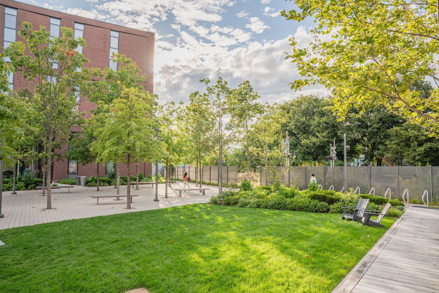 Modern campus grounds featuring manicured lawns, paved paths and brick buildings.