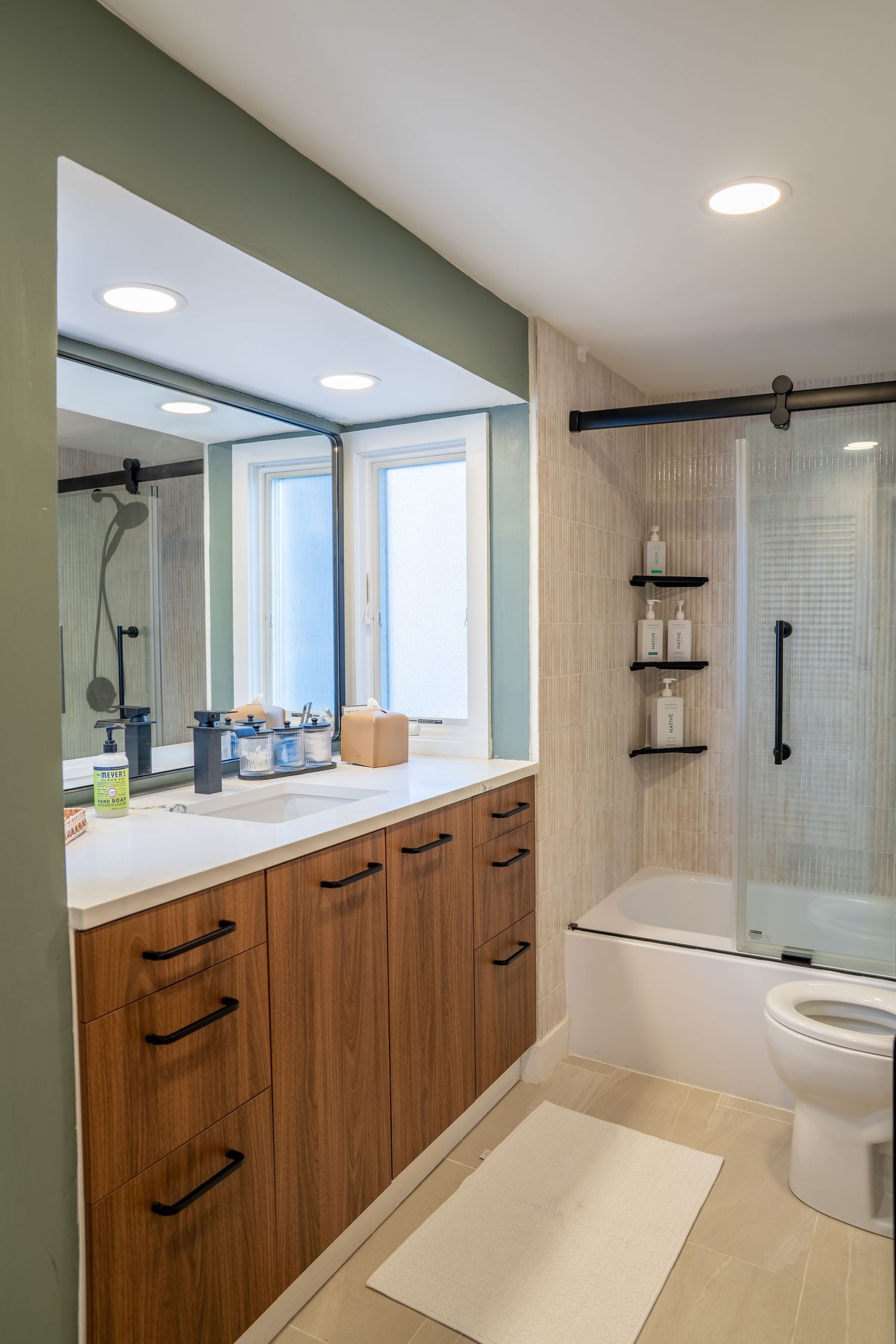Modern bathroom interior with wooden cabinets, white countertops and recessed lighting showcases sleek minimalist design.