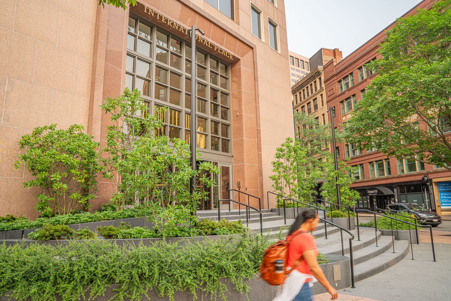 Accessible ramp entrance to brick building with ornate architectural details and greenery.