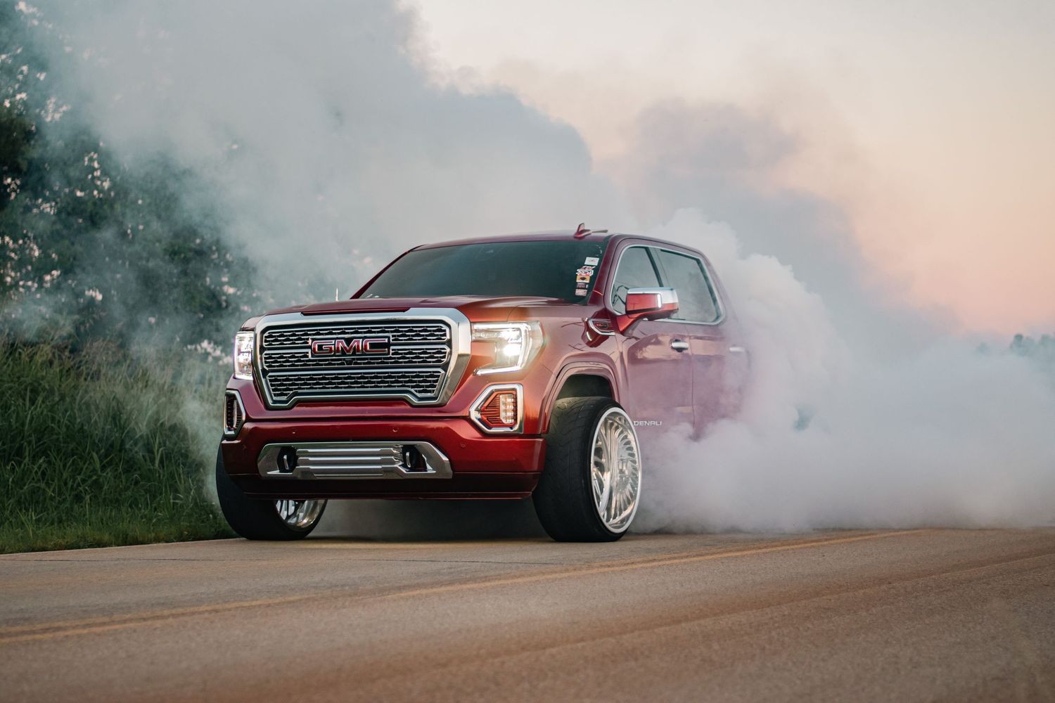 Powerful automotive photography of a lifted GMC Sierra burning out, captured with bold smoke, custom styling, and dynamic street energy.