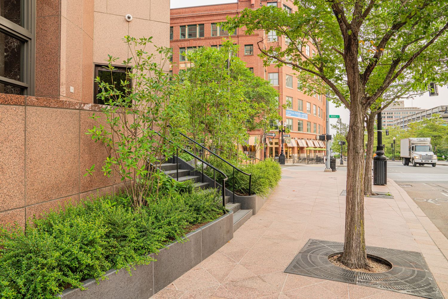 Modern brick university building entrance with glass windows and landscaped walkway on a sunny day.