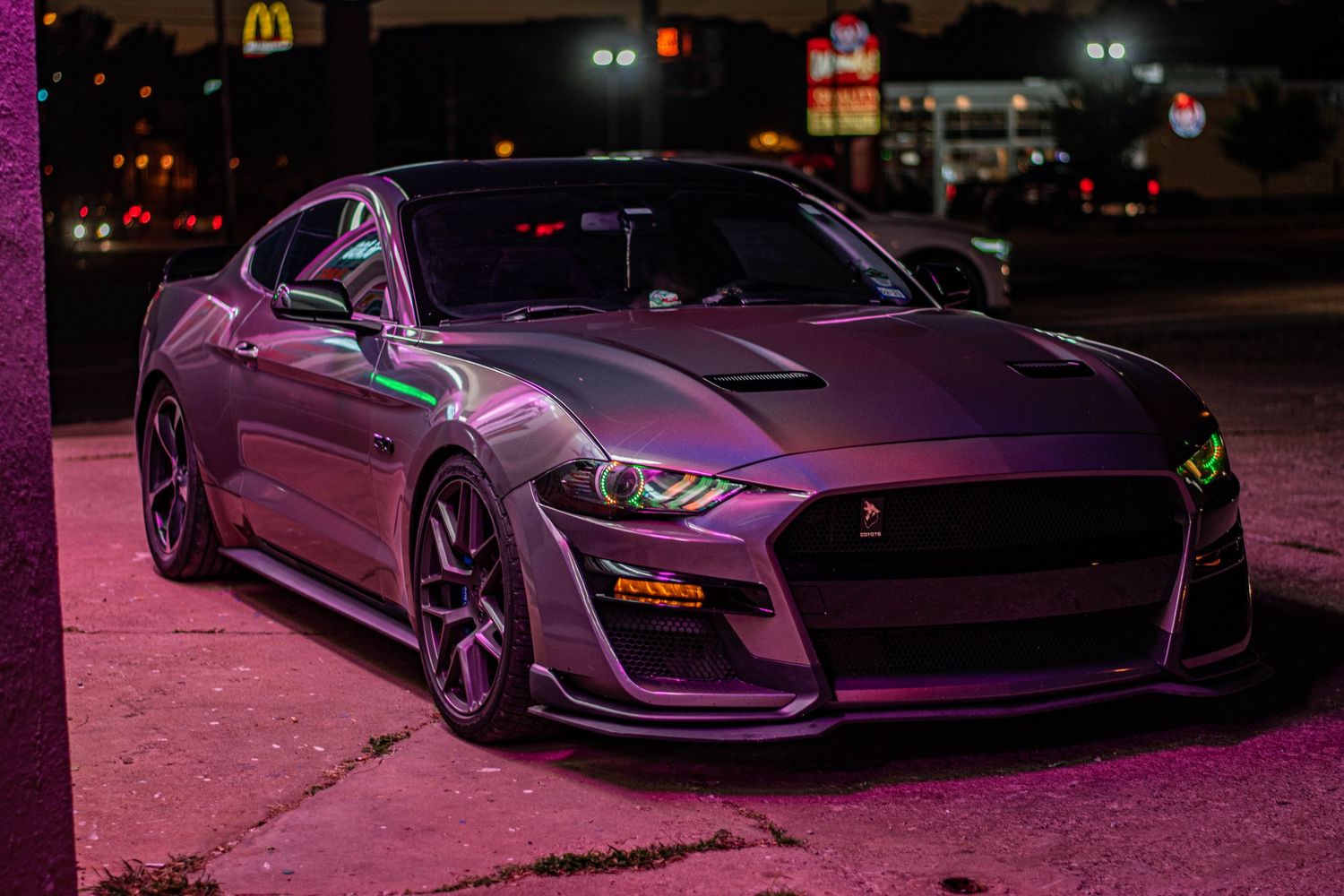 Vibrant night car photography of a Ford Mustang Shelby, highlighted by neon lighting, sleek design, and bold street performance style.