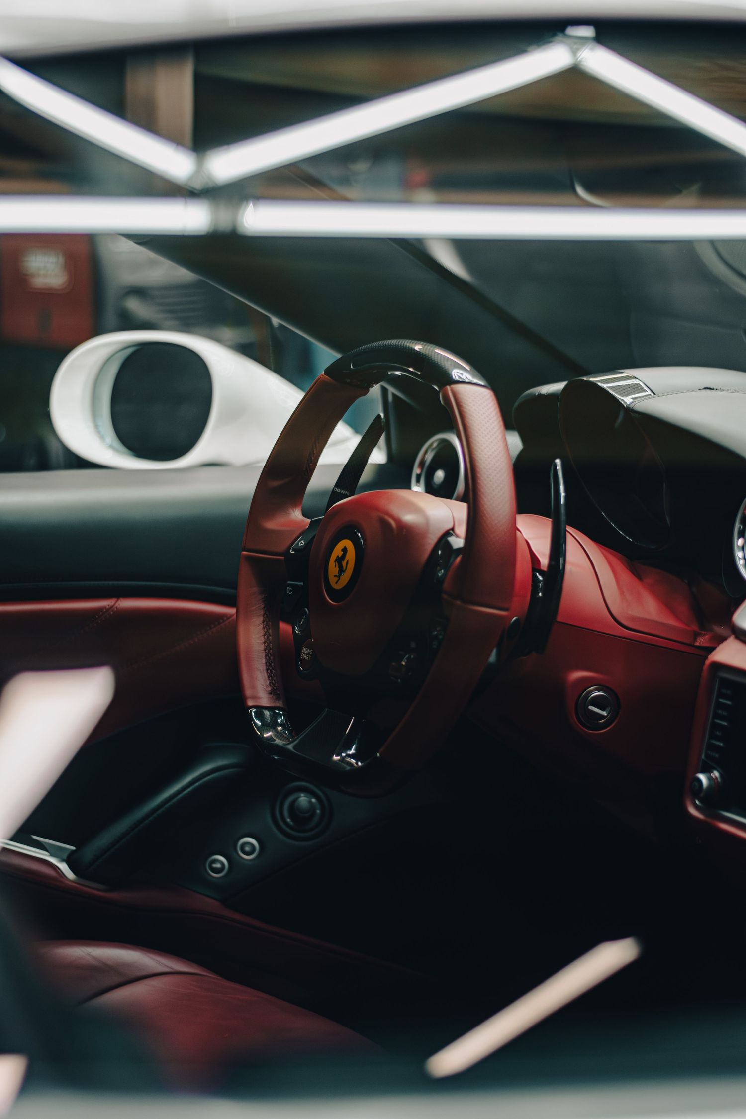 Luxury automotive interior photography of a Ferrari, showcasing red leather, sleek design, and refined details through a modern perspective.
