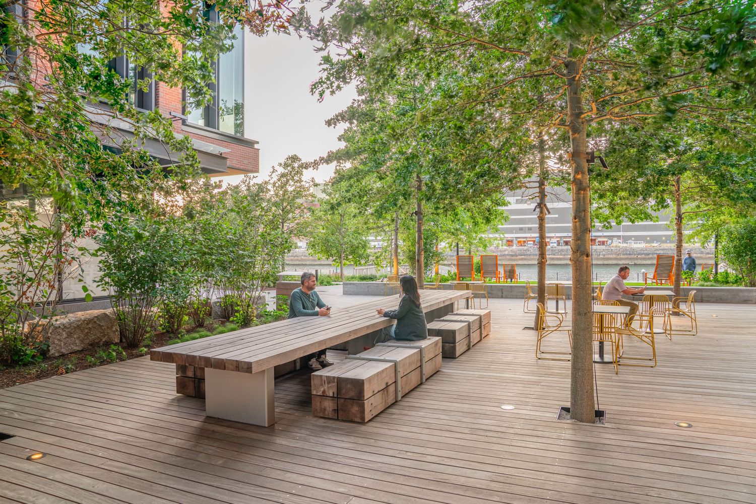 Wood-decked terrace with built-in benches and trees providing natural shade.