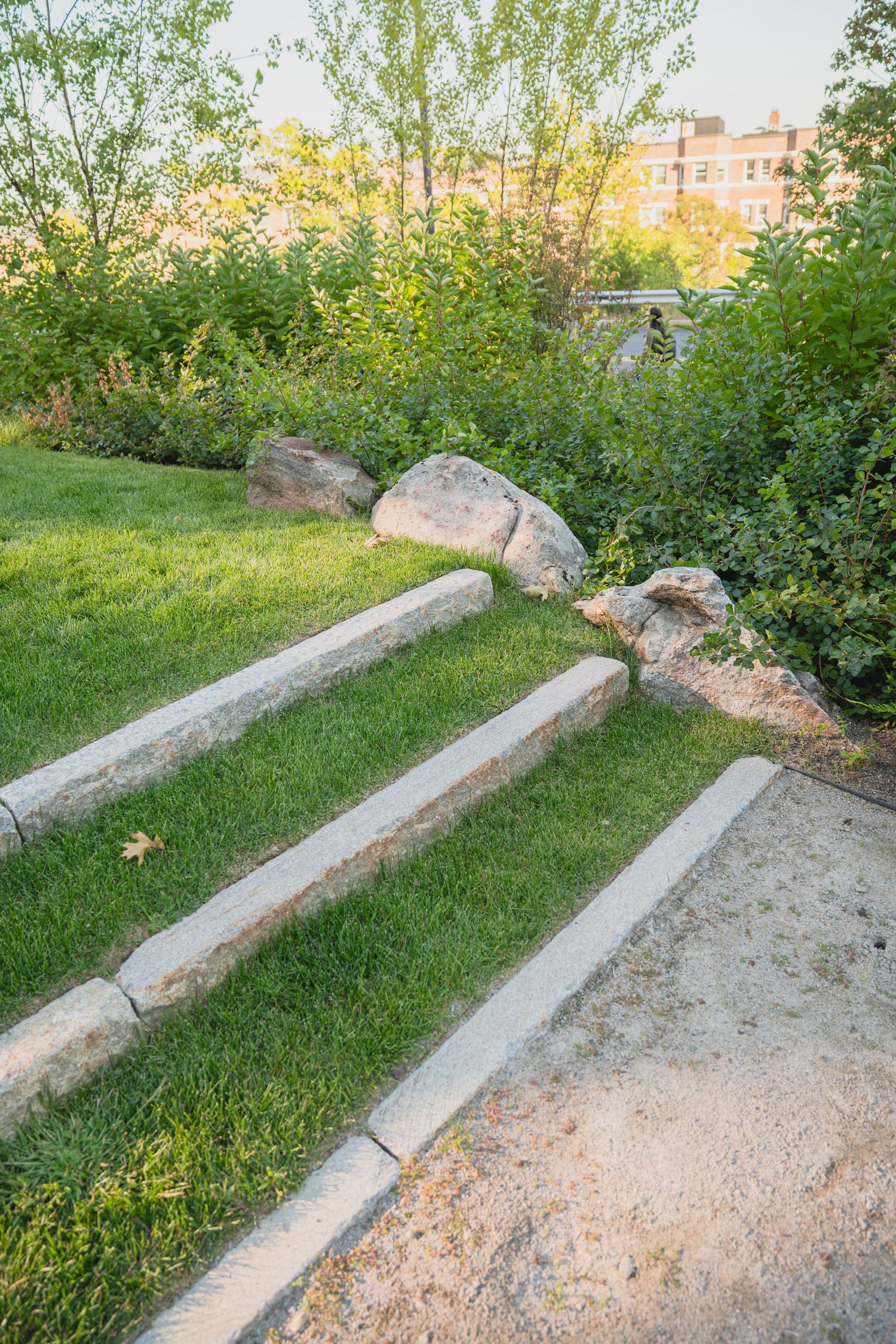 Concrete benches and boulders arranged along a grassy landscaped area.