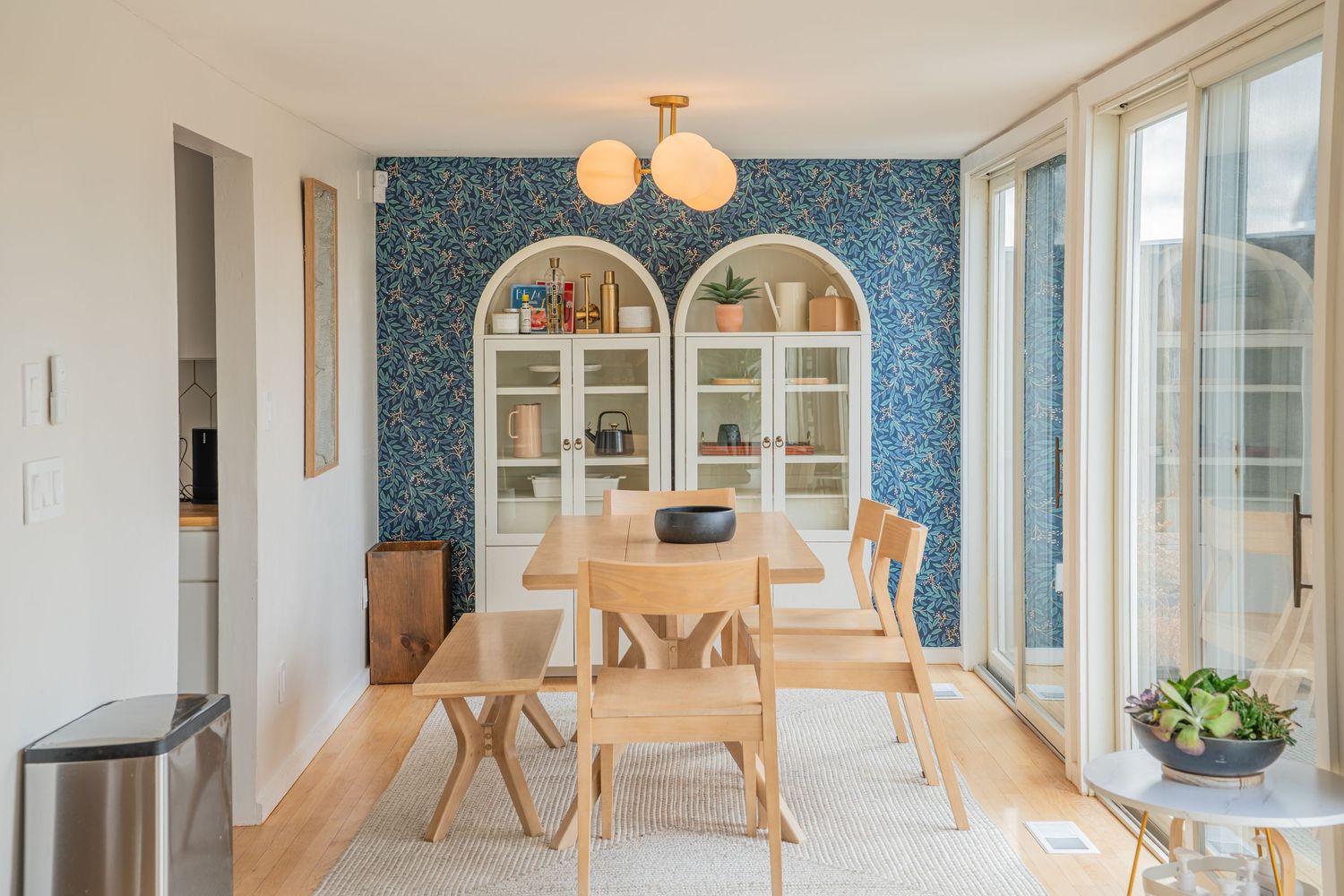 Modern Scandinavian apartment interior with white walls, wood floors, and blue accent wall features globe pendant lights.