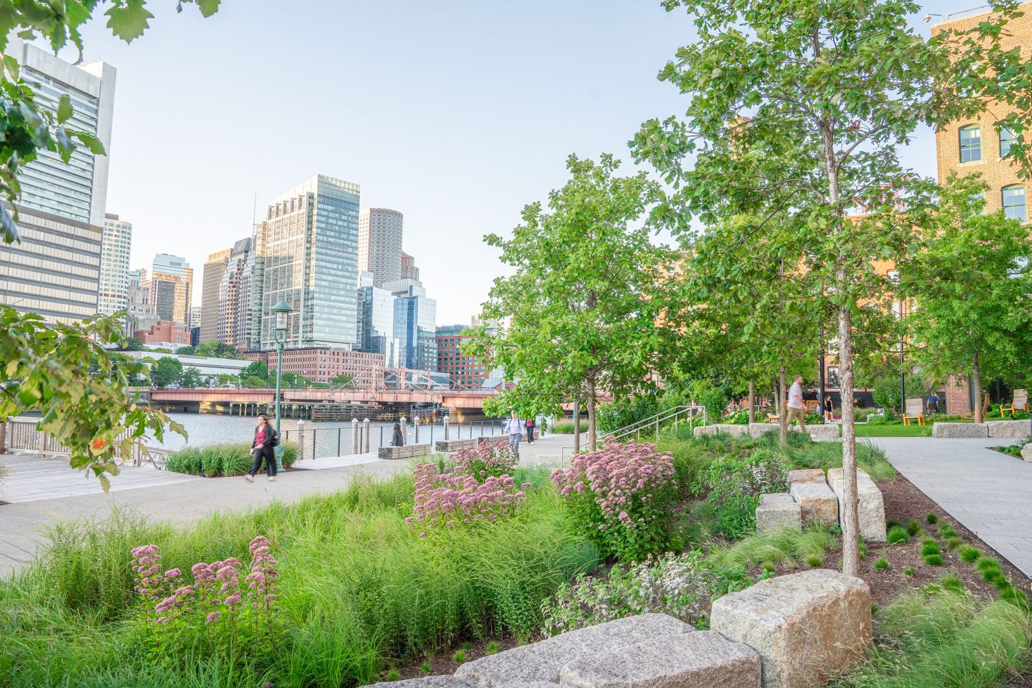 Elevated walkway with city skyline views and natural landscaping elements.