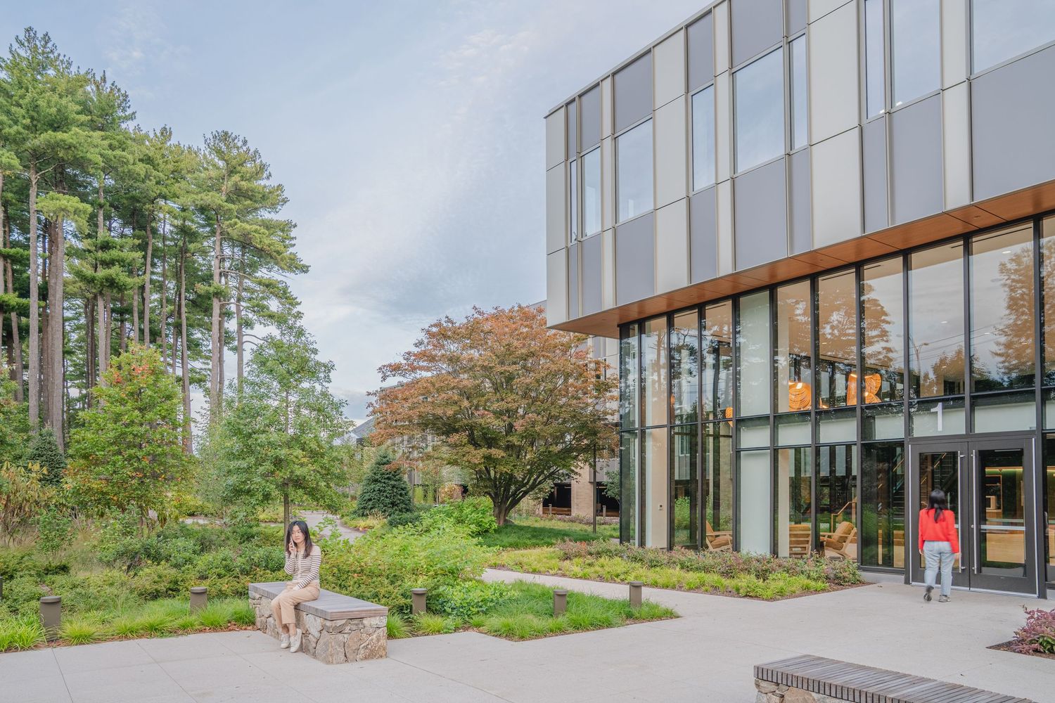 Modern glass building exterior with connecting pathways and natural landscaping.
