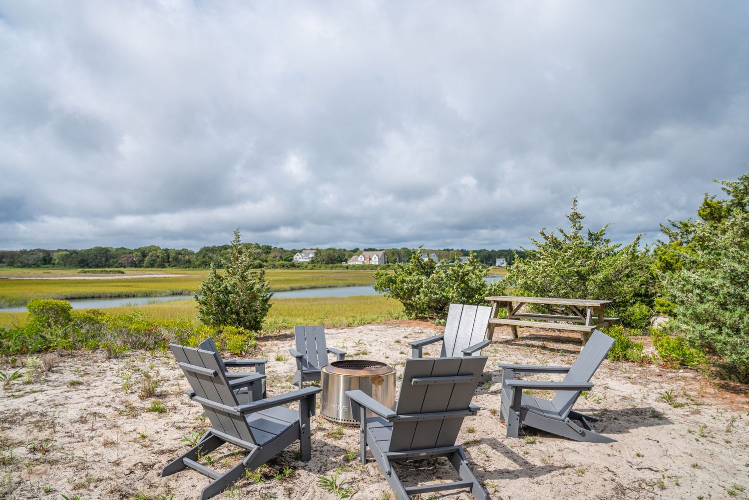 Professional photography of panoramic sequence of Adirondack chairs overlooking a coastal marsh landscape under dramatic cloudy skies.