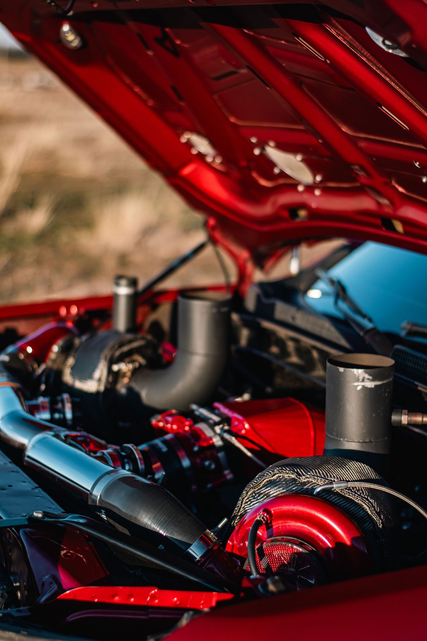 Detailed automotive photography of a custom GMC Sierra engine bay, showcasing polished performance parts, red accents, and powerful design.