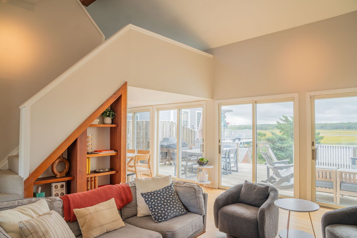 Modern coastal home interior with open concept living space and large windows overlooking water views.