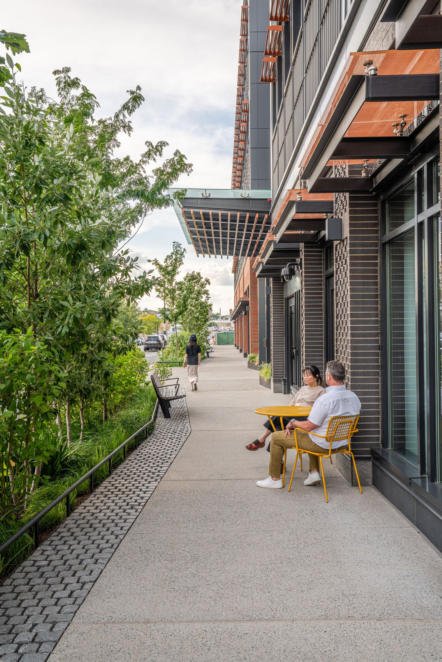 Modern building terrace with outdoor seating area and lush green landscaping.