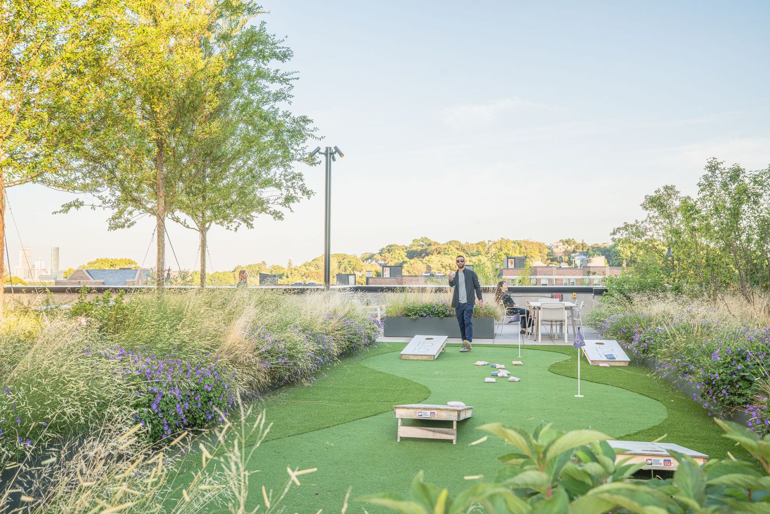 Rooftop garden area featuring green lawn space and outdoor seating with city views.