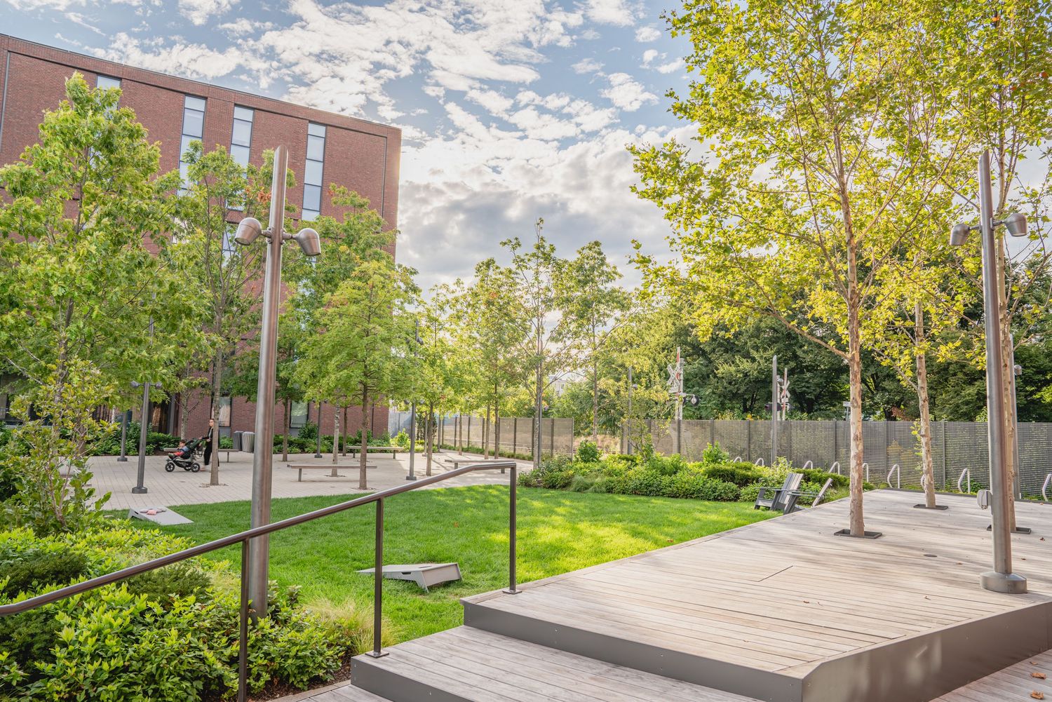 Campus walkway with trees and landscaping between brick buildings on a sunny day.