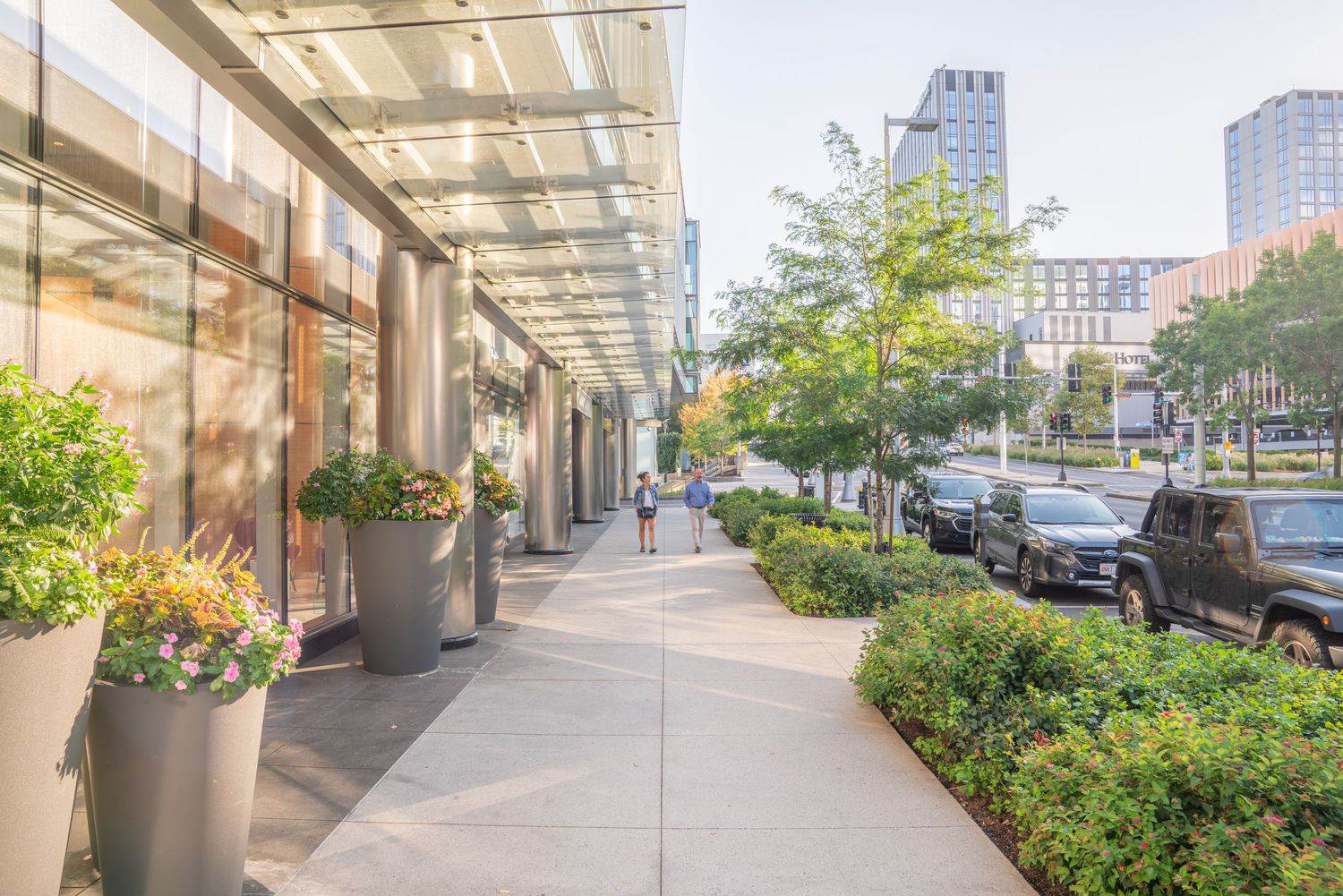 Commercial building entrance with planters and pedestrian walkway in an urban setting.