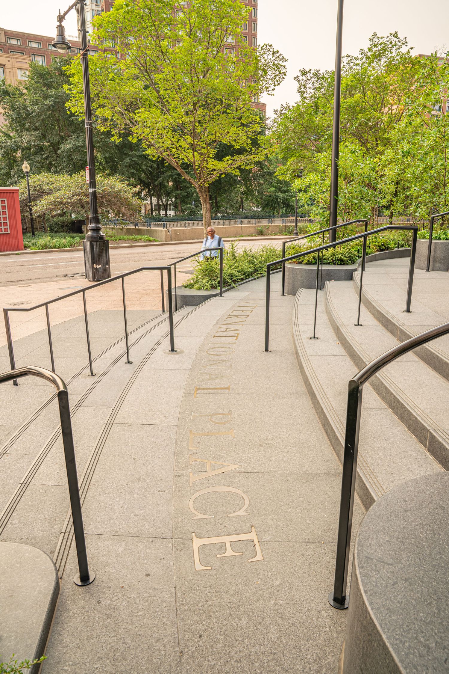 Series of concrete steps with black handrails leading up to building entrance.