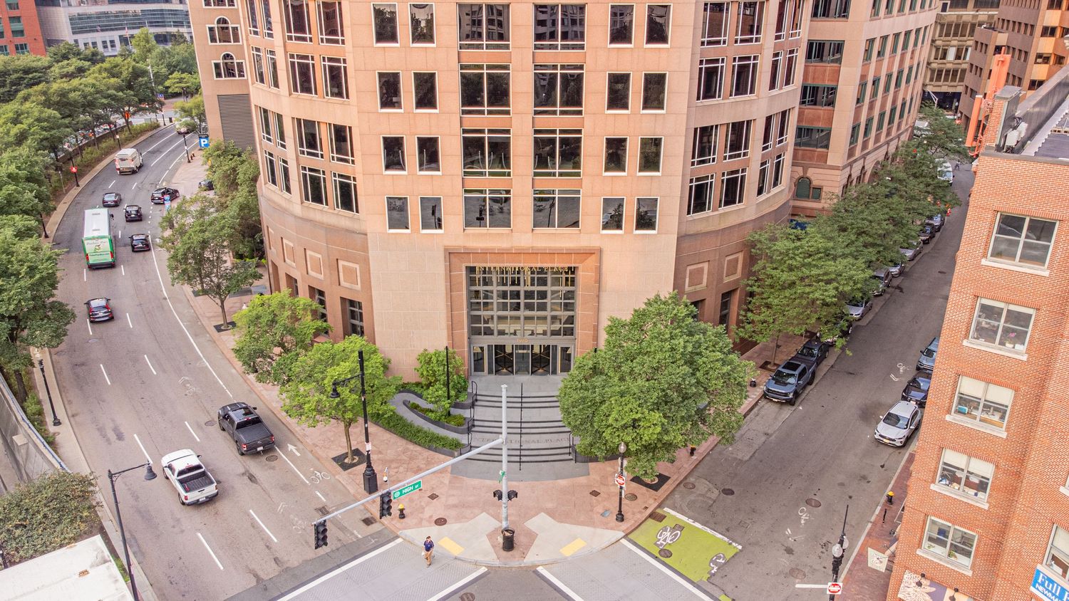 Aerial panoramic view of urban campus building with surrounding streets and landscaping.