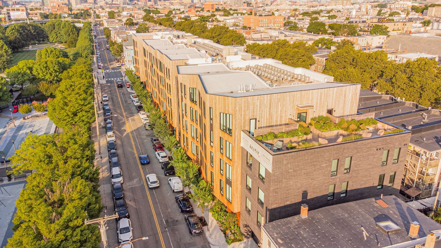 Bird's eye view of multi-story apartment complex with parking lots and tree-lined streets.