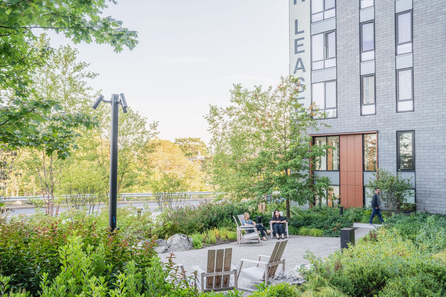 Garden seating area with chairs between modern residential buildings.
