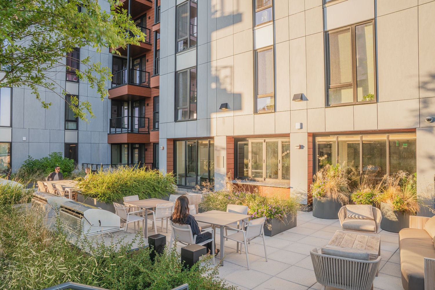 Modern residential complex with landscaped courtyard and outdoor seating areas.