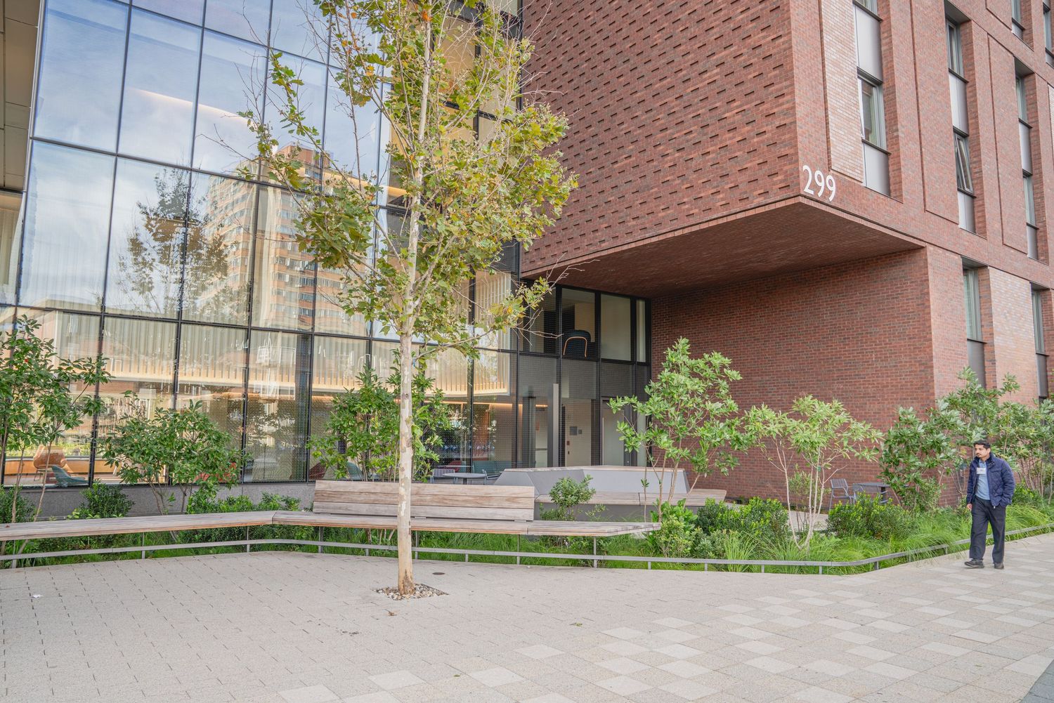 Brick building entrance with paved walkway and landscaped garden areas.