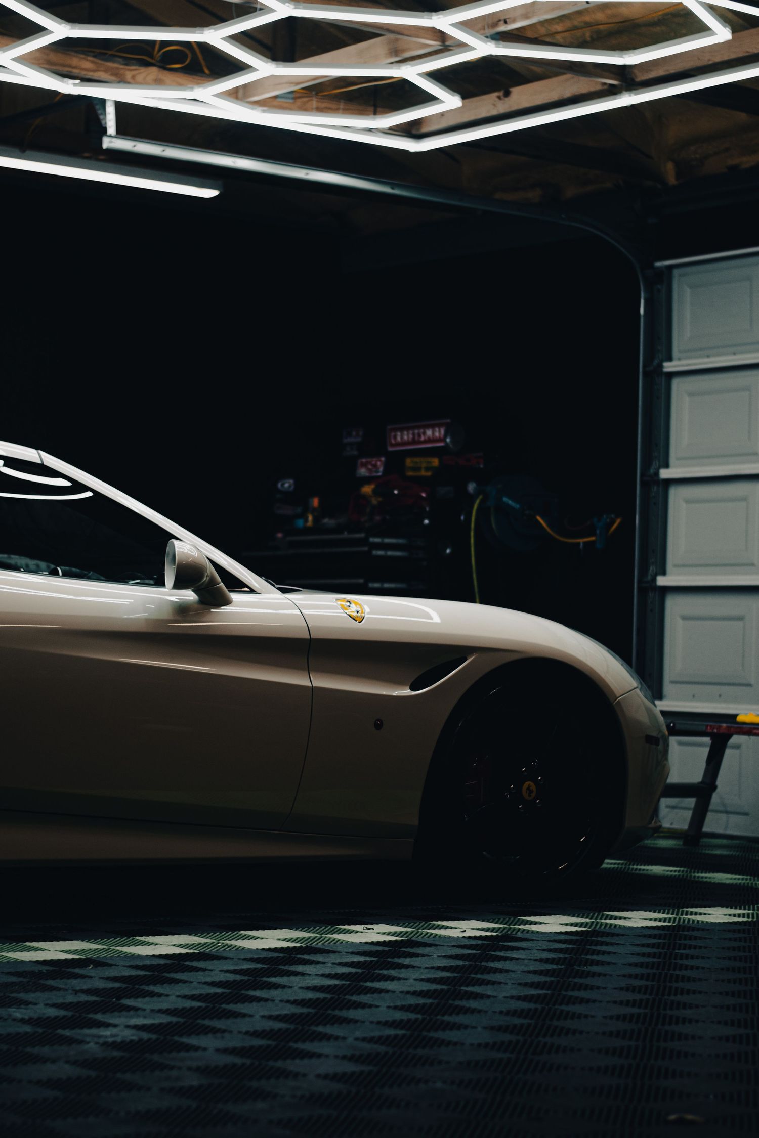 Luxury Ferrari detail shot in a garage, featuring sleek design, dramatic lighting, and modern styling for bold automotive photography.