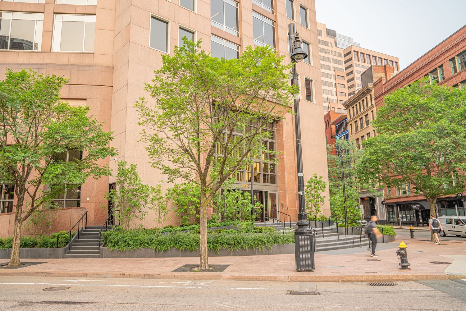 Wide angle view of a beige institutional building exterior with glass windows and trees.