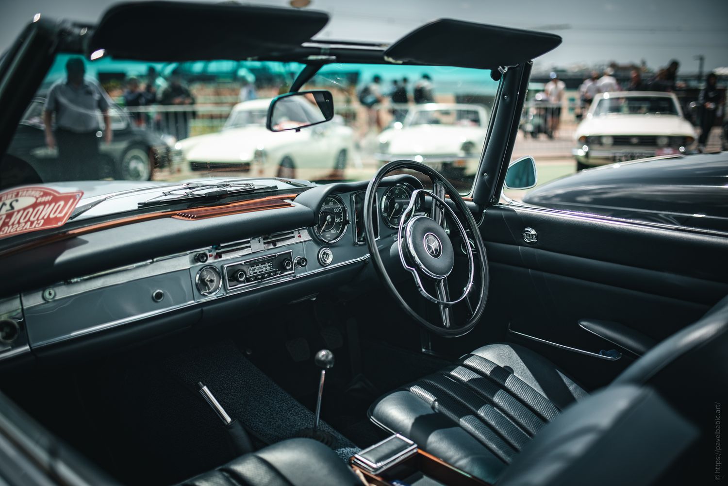 Interior view of a vintage convertible car showcasing its sleek black leather seats and classic dashboard with chrome accents.