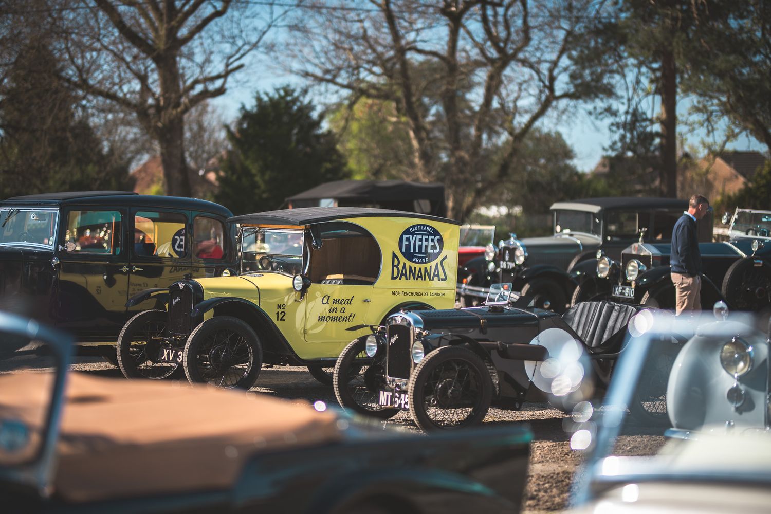 A vintage car show featuring a yellow delivery truck with 