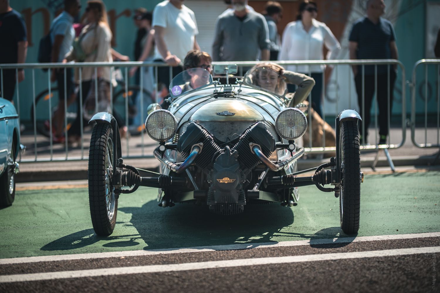 A vintage car with a sleek design is showcased in front of a crowd, highlighting its classic features and unique charm.