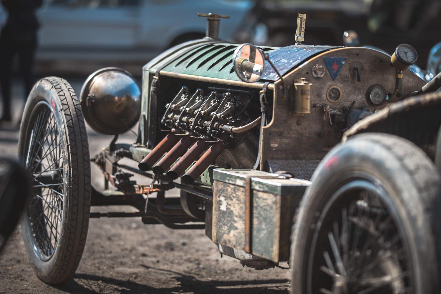 Close-up of a vintage race car showcasing its unique engine, retro design, and weathered details in a dusty outdoor setting. 1913 Monarch V8