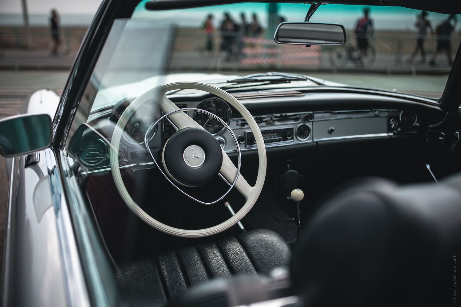 A close-up of a vintage car's interior featuring a stylish steering wheel, leather seats, and classic dashboard details.