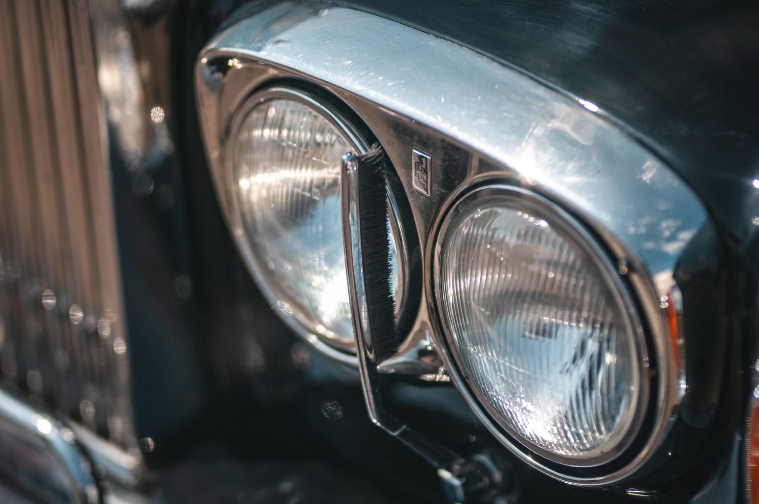 Close-up of classic car headlights with polished chrome trim, showcasing vintage design and elegance.