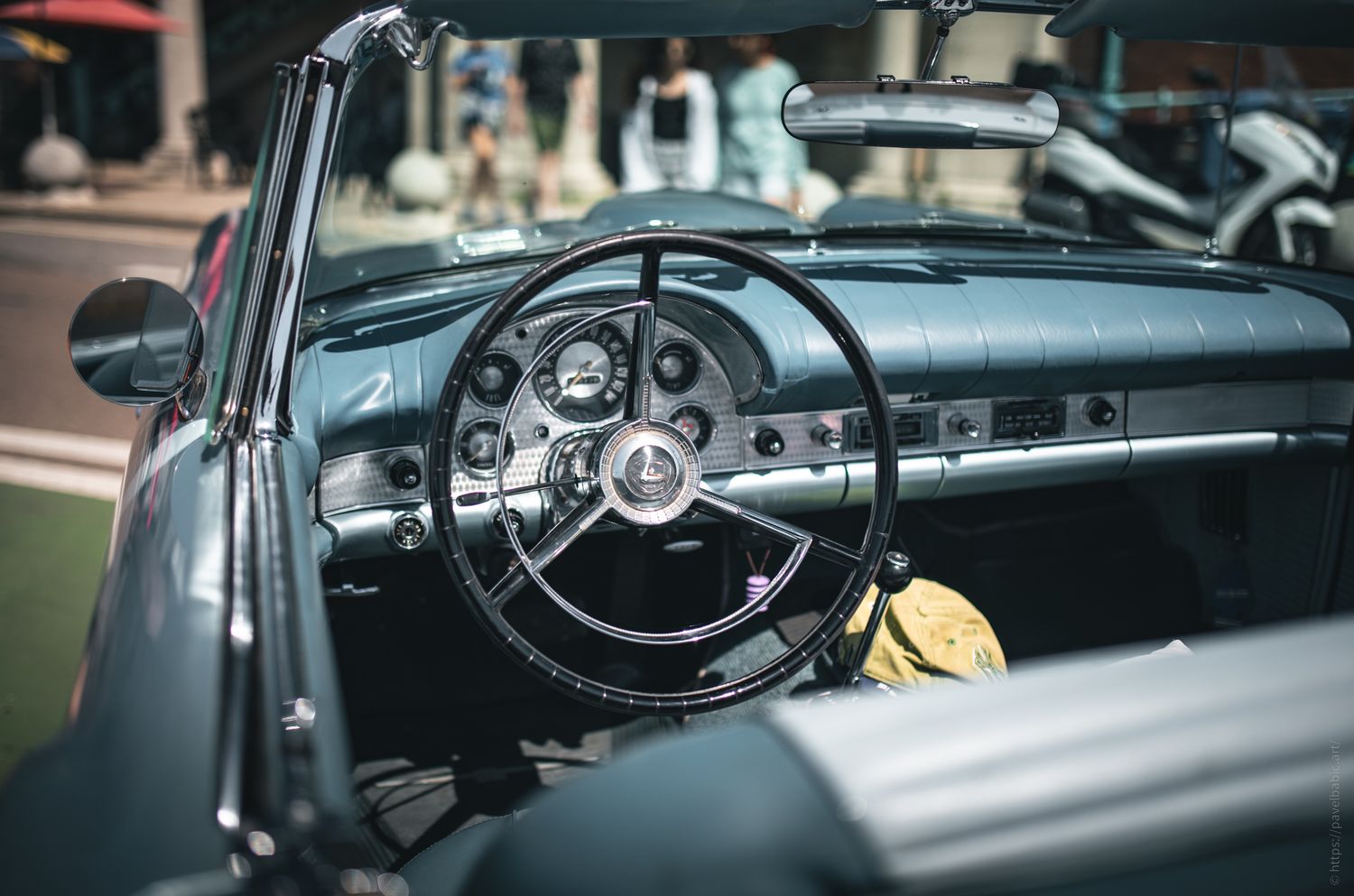 Interior of a classic convertible car with a vintage steering wheel and dashboard, showcasing its retro design elements.