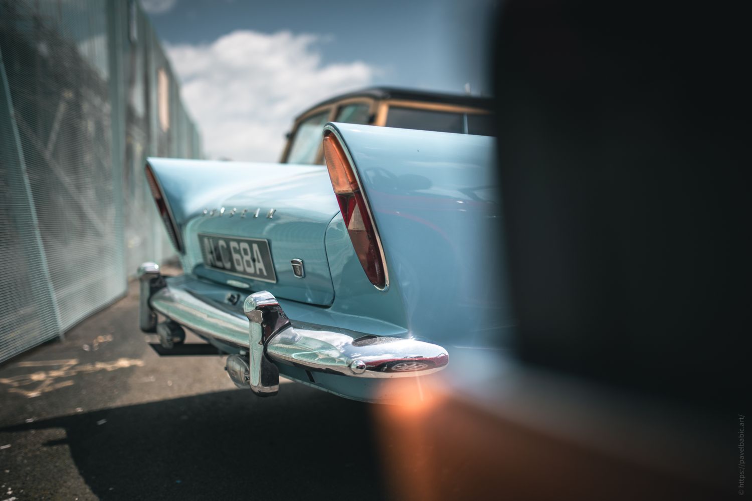 A vintage blue car with distinctive tail fins and chrome detailing, parked against a blurred background, exuding a classic charm.