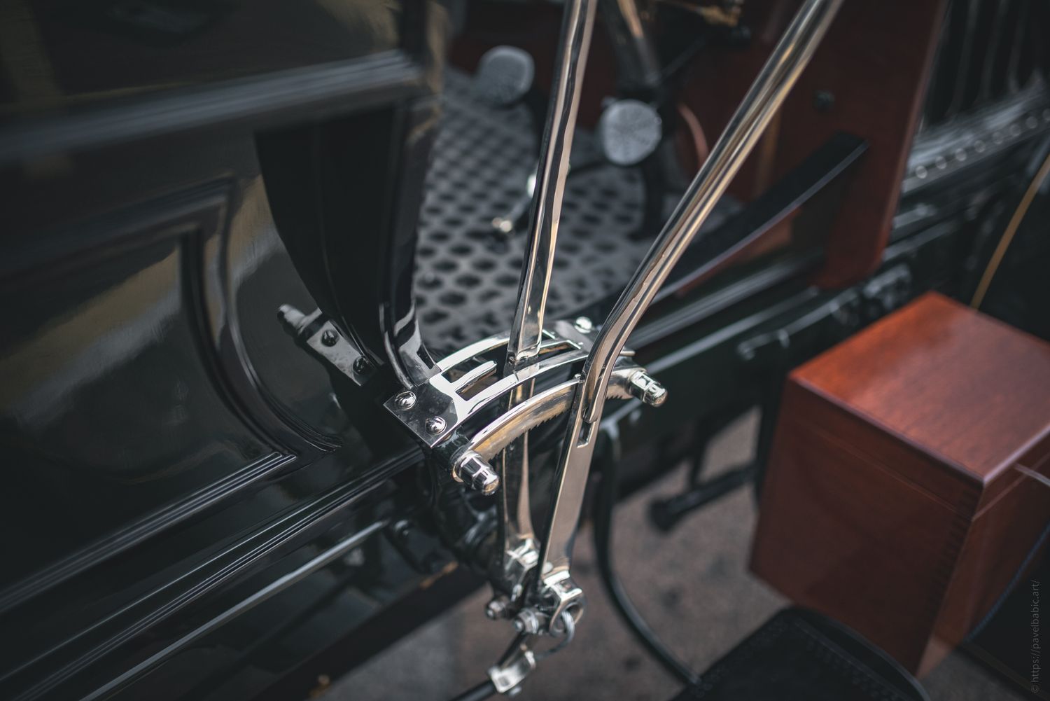 Close-up of vintage car controls, featuring polished metal levers and intricate metalwork on a dark background.