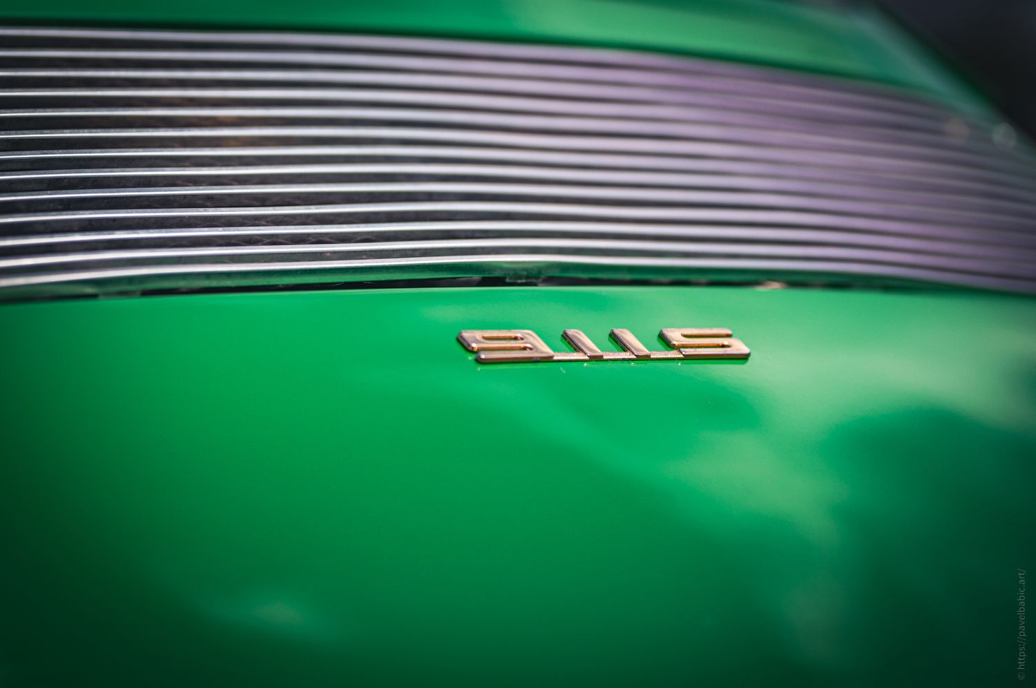 Close-up of a shiny green car hood displaying the elegant 