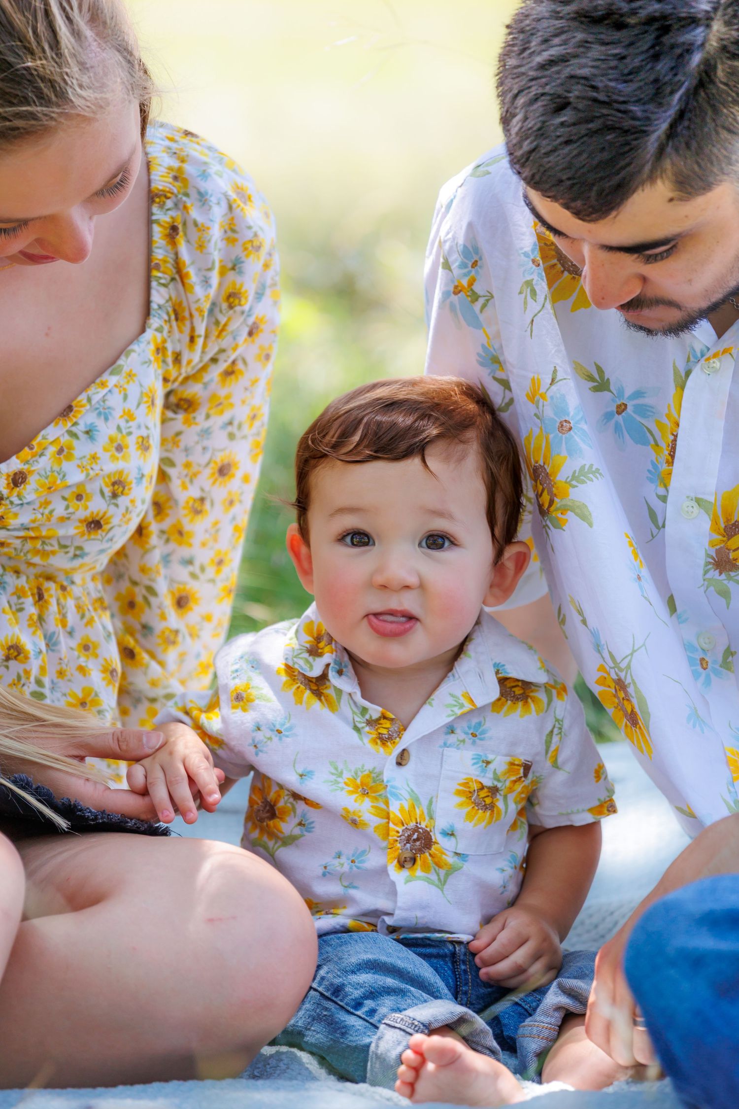Family wearing coordinating yellow floral outfits sitting together outdoors.