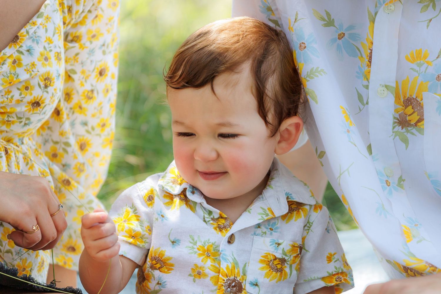 A child sits under a floral patterned curtain with sunlight streaming through creating a dreamy atmosphere.