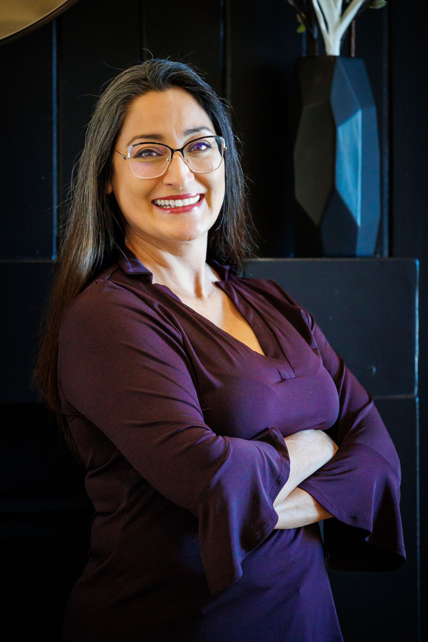 Professional headshots of someone in a purple blazer smiling against a dark background.